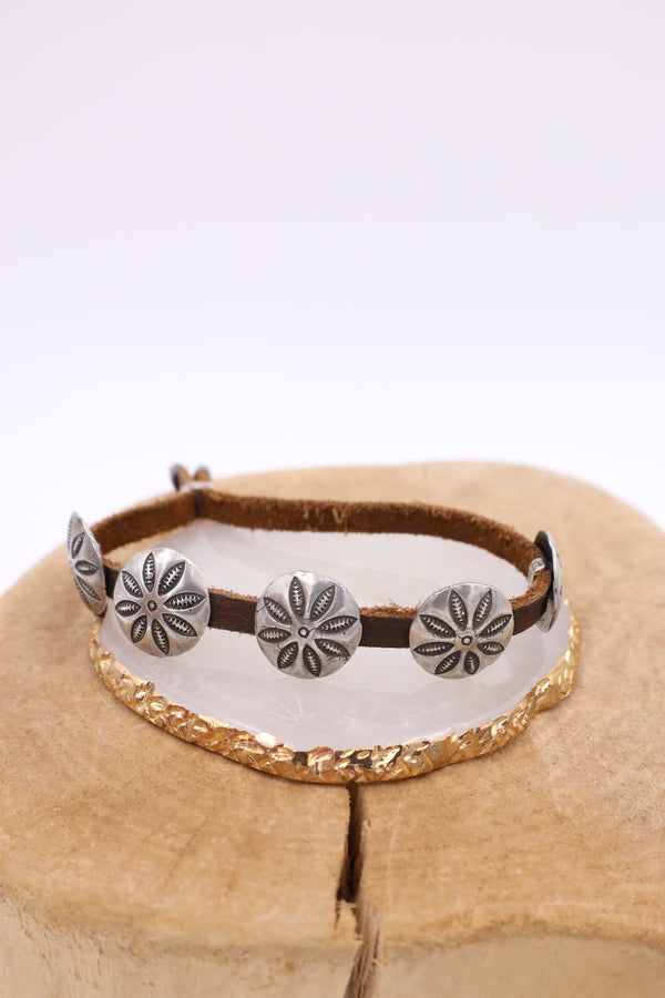 Leather cinch bracelet with sterling silver concho charms.