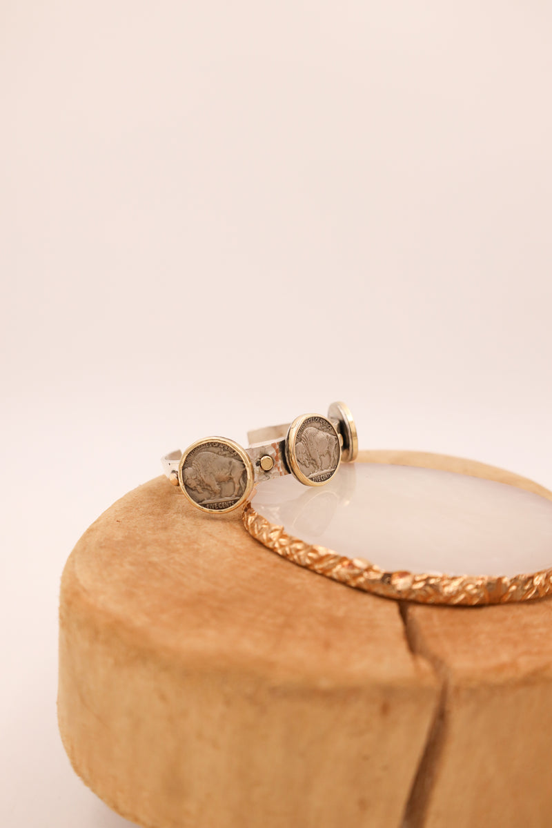 Sterling silver hammered cuff with three buffalo nickels with gold rims and gold dots in between the coins 