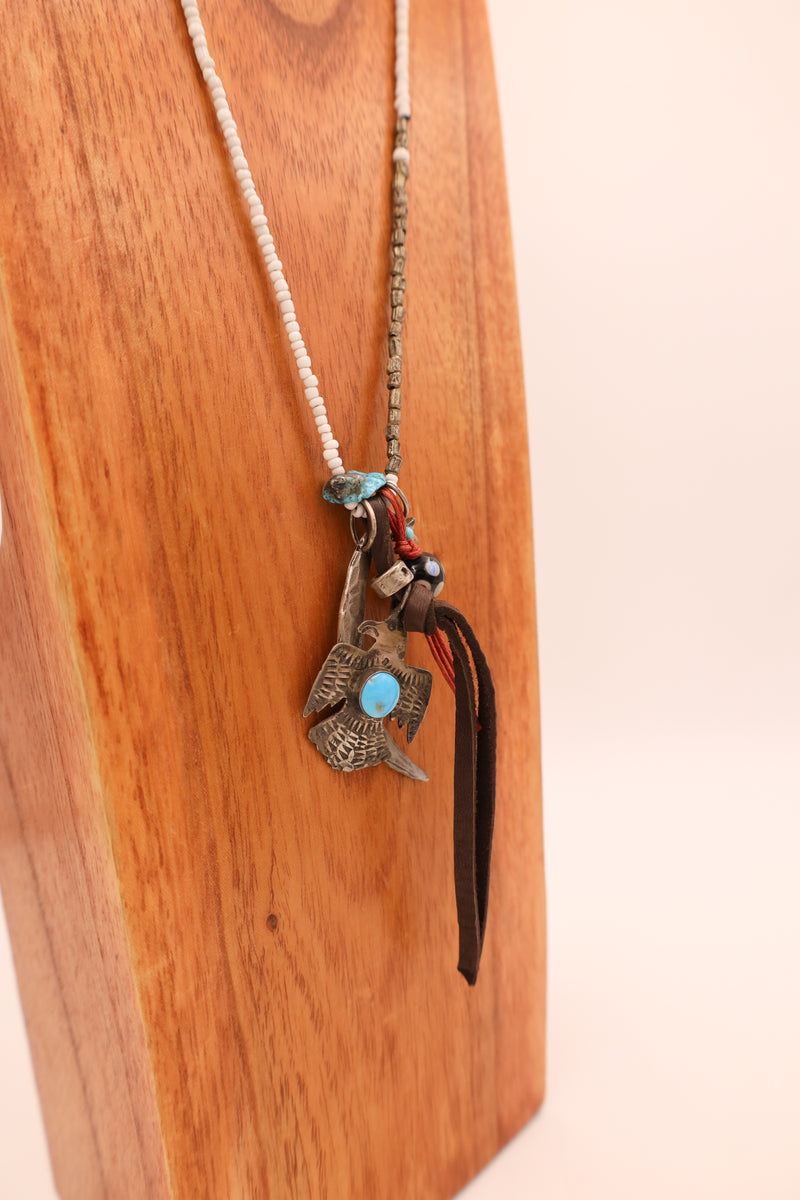 Bead necklace with sterling silver crescent moon charm, star with turquoise dot, thunderbird with turquoise stone in center, leather strand and polka dot ball charms. 