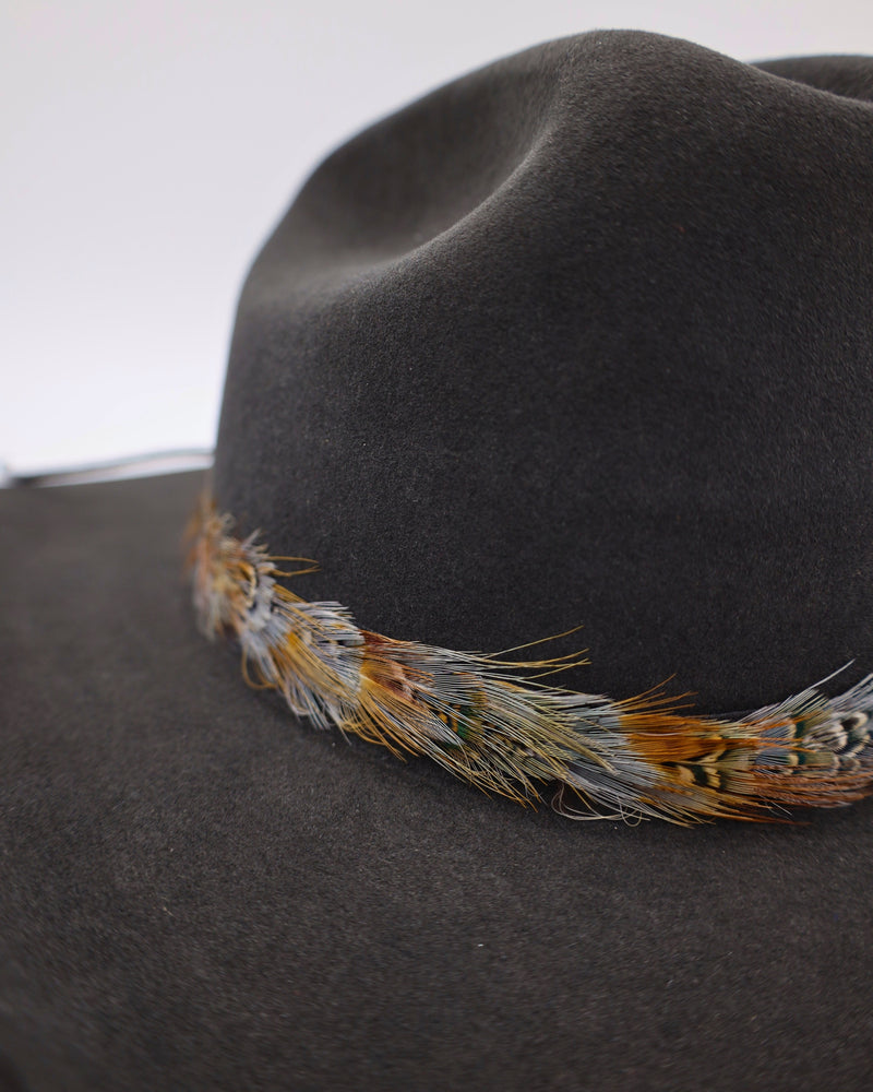 Pheasant feather hat band with leather ties in the back portion.