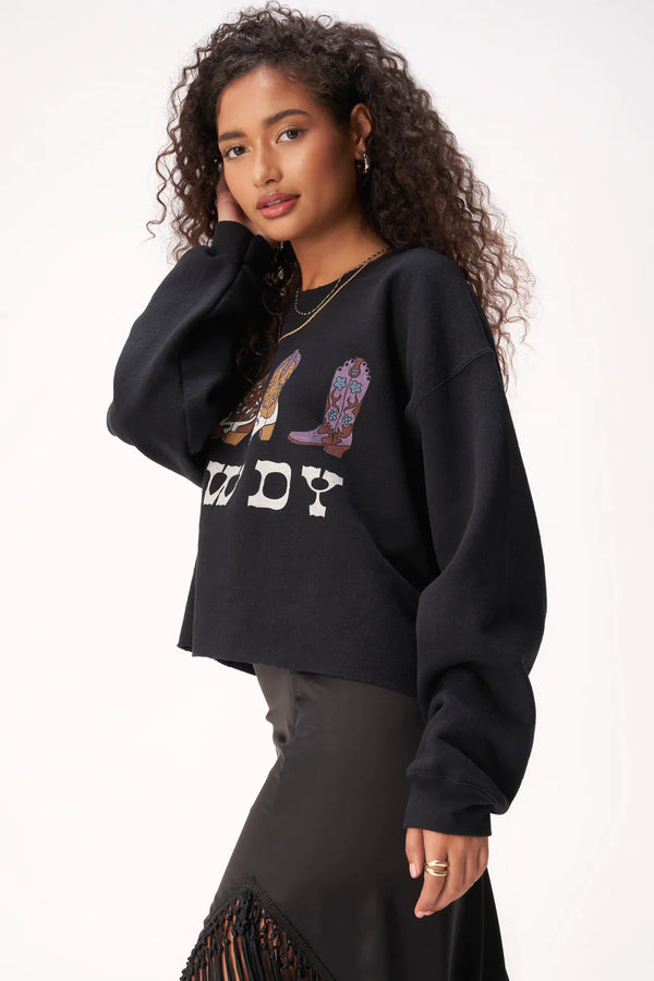 Women wearing a cropped, raw edge hem with a boxy silhouette, with crewneck is plenty roomy! A long sleeve pullover with bold "howdy" text and cowboy boot graphic across the front.