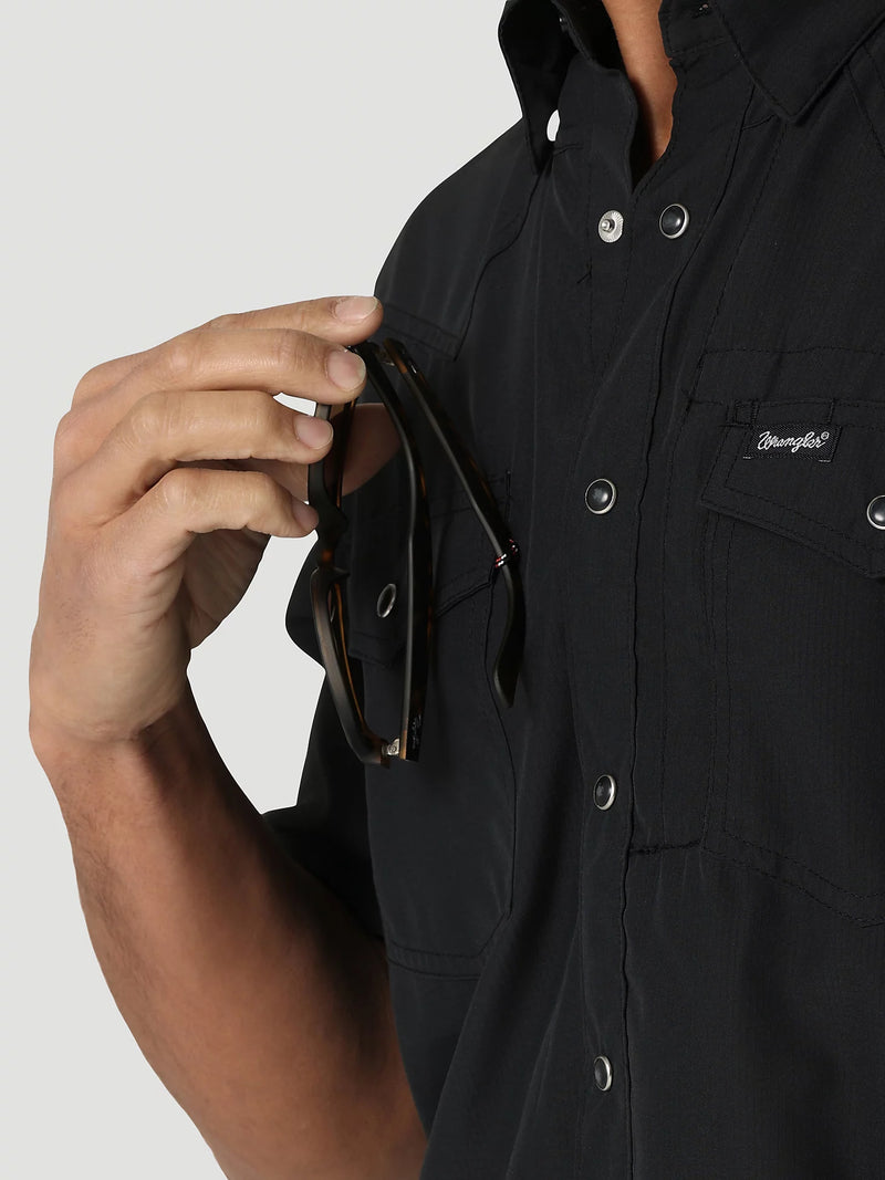 Person wearing a black shirt with a brand logo, holding sunglasses.
