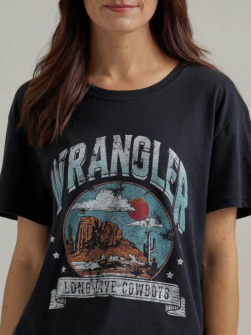 Woman wearing black t-shirt with with image of a desert scene and script "Wrangler Long Live Cowboys"