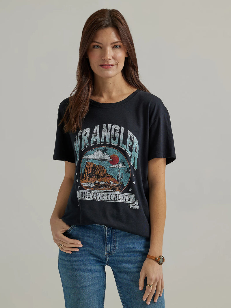 Woman wearing black t-shirt with with image of a desert scene and script "Wrangler Long Live Cowboys"