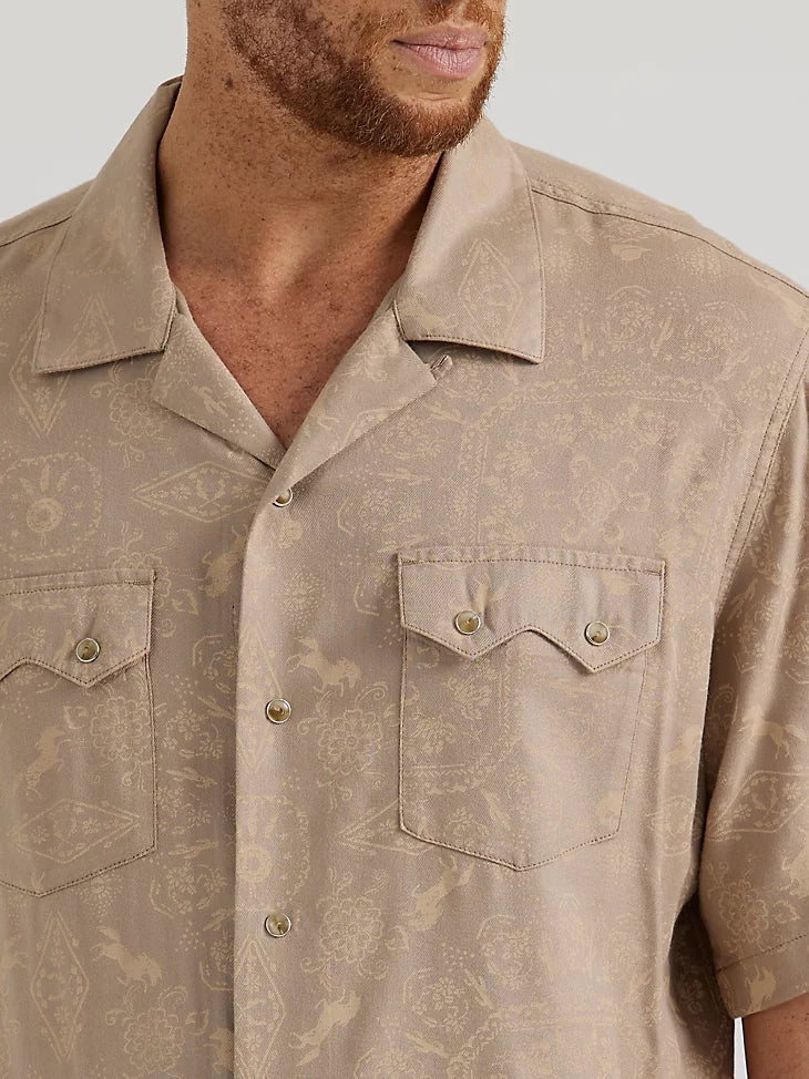 Man wearing tan short sleeve button down with subtle lighter tan design