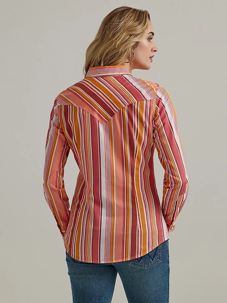 Woman wearing striped shirt in warm tones with pearl snap closure and long sleeves