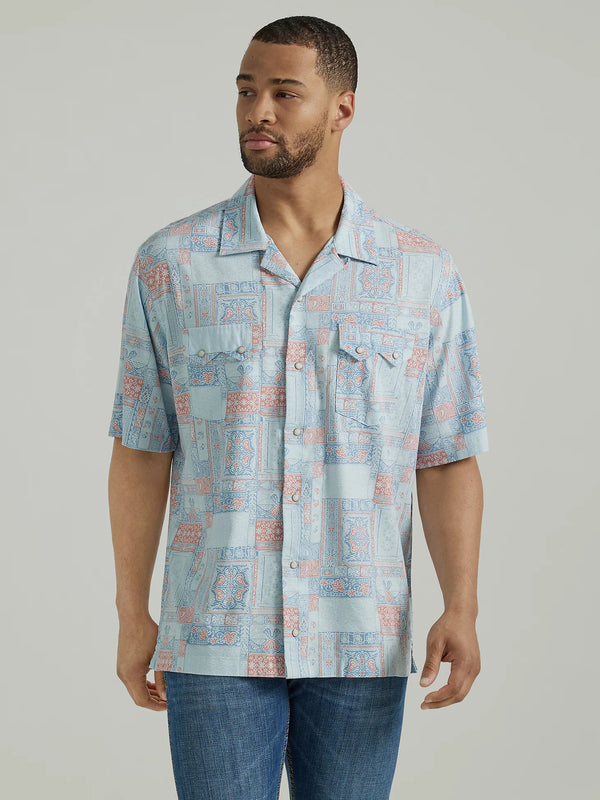 Man wearing short sleeve pearl snap shirt with multi color pattern throughout