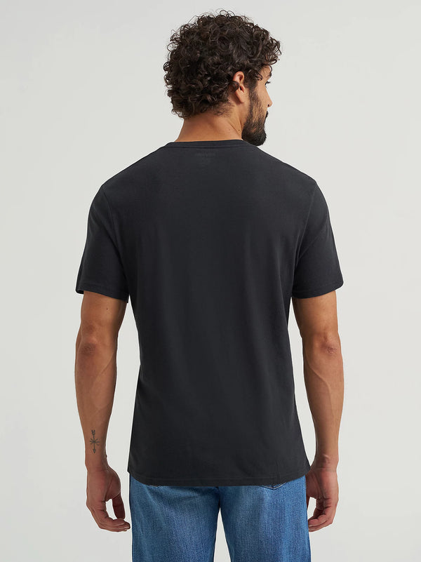 Man wearing a black t-shirt and blue jeans on a plain background