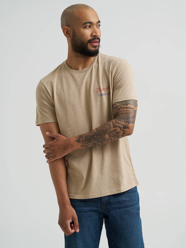 Man wearing a beige t-shirt with a logo on a plain background