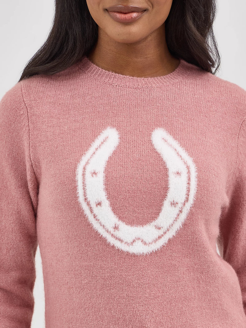 Pink sweater with a white horseshoe design on a plain background