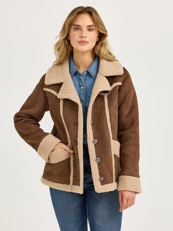 Woman wearing a brown shearling jacket with beige interior on a white background