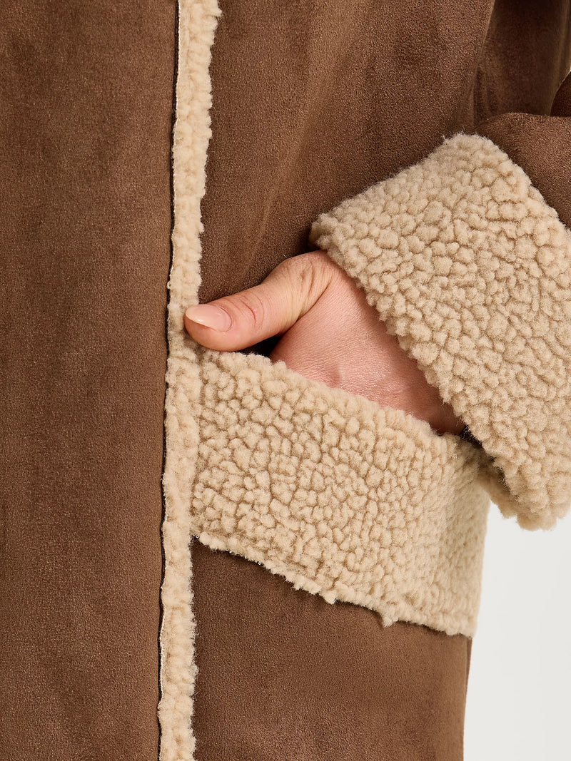 Close-up of a brown coat with beige sherpa lining on a white background