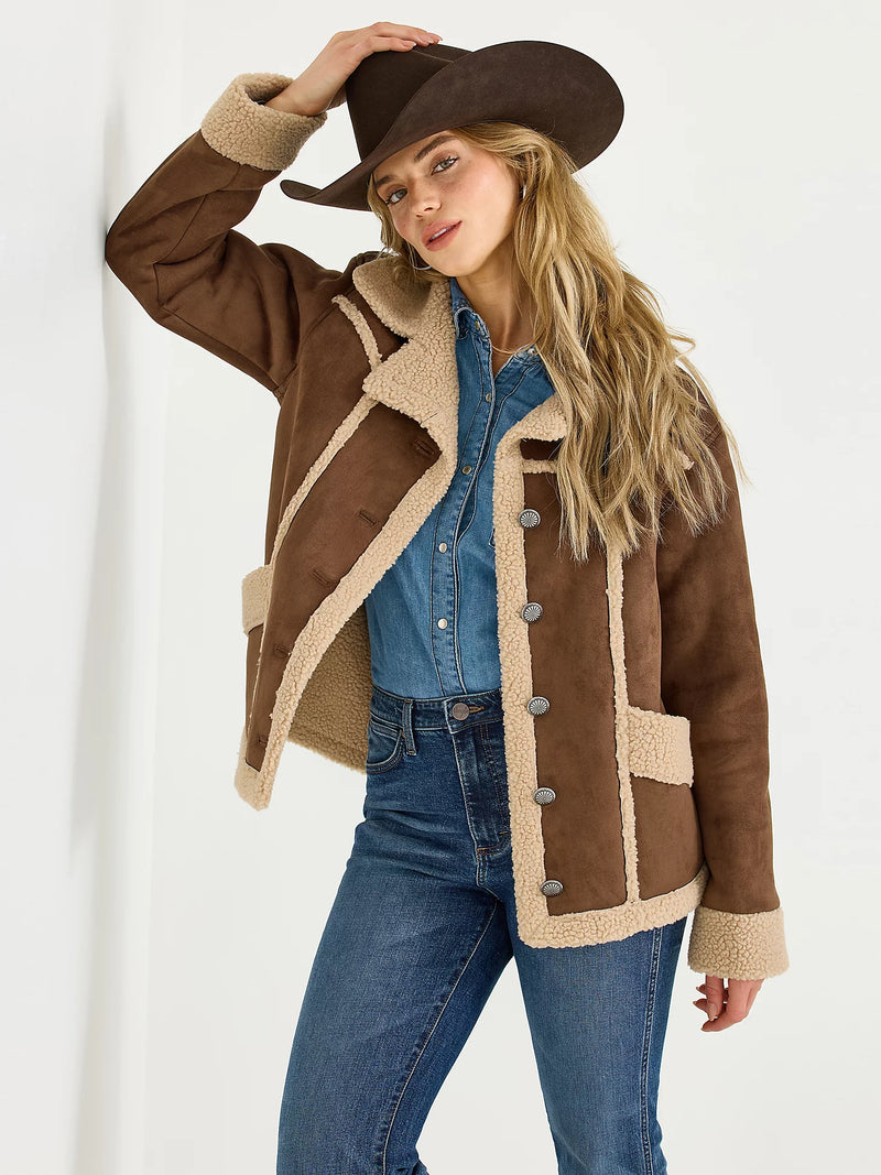 Woman wearing a brown shearling jacket and hat on a white background