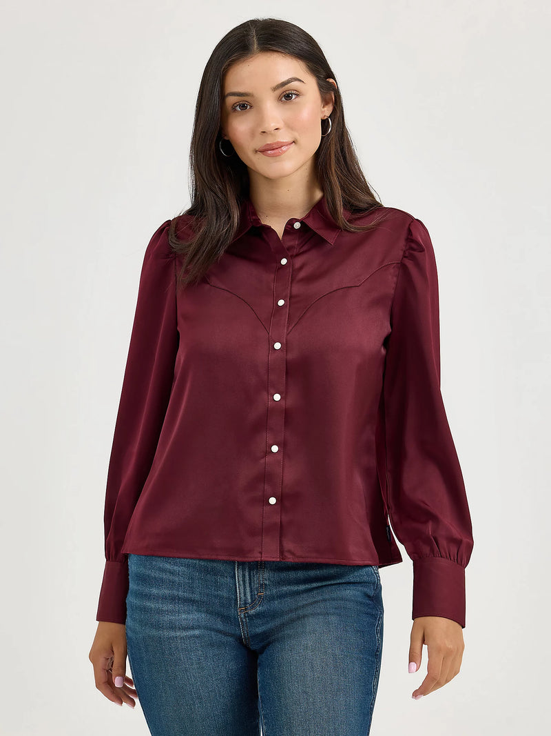 Woman wearing a burgundy blouse with blue jeans on a white background