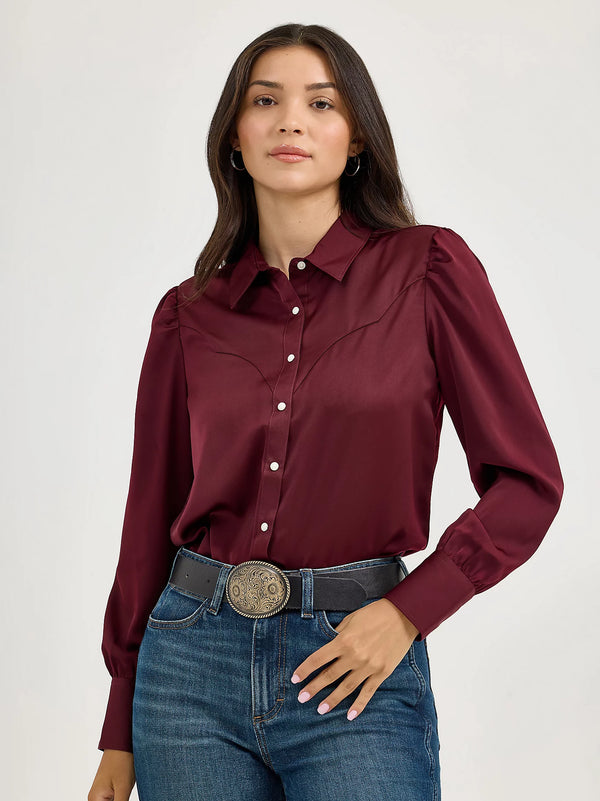 Woman wearing a burgundy shirt and blue jeans on a white background
