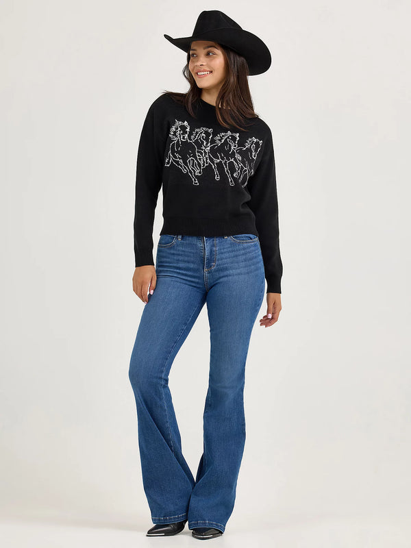 Woman wearing a black sweater with horse design and blue jeans on a white background