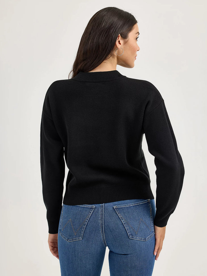 Person wearing a black sweater and blue jeans on a light gray background