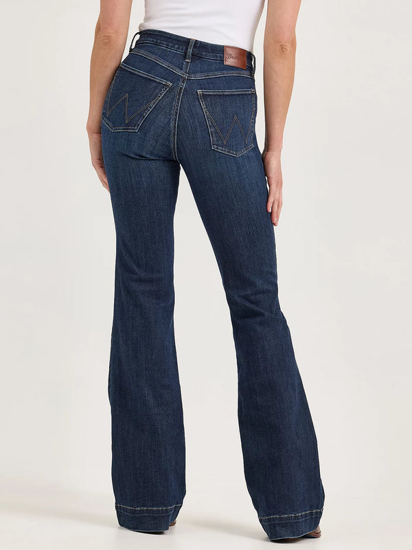 Dark blue flared jeans worn by a person on a white background