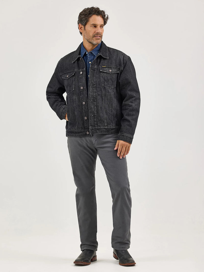 Man wearing a dark denim jacket and gray pants on a white background
