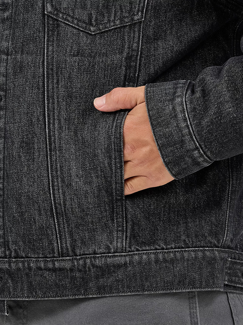 Close-up of a person wearing a dark denim jacket with a hand in the pocket.
