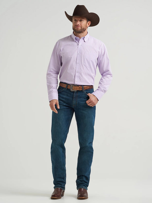 Man wearing a light purple shirt, dark blue jeans, and a brown cowboy hat on a white background
