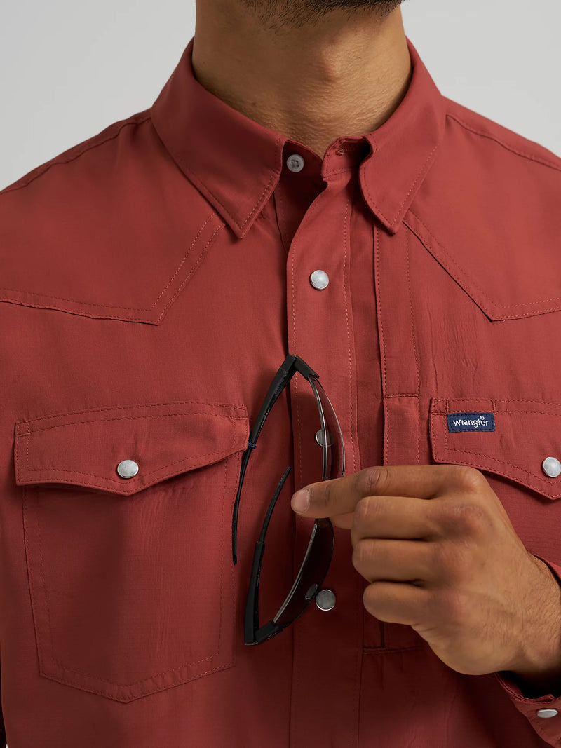 Person wearing a red shirt with a visible brand logo, holding sunglasses.