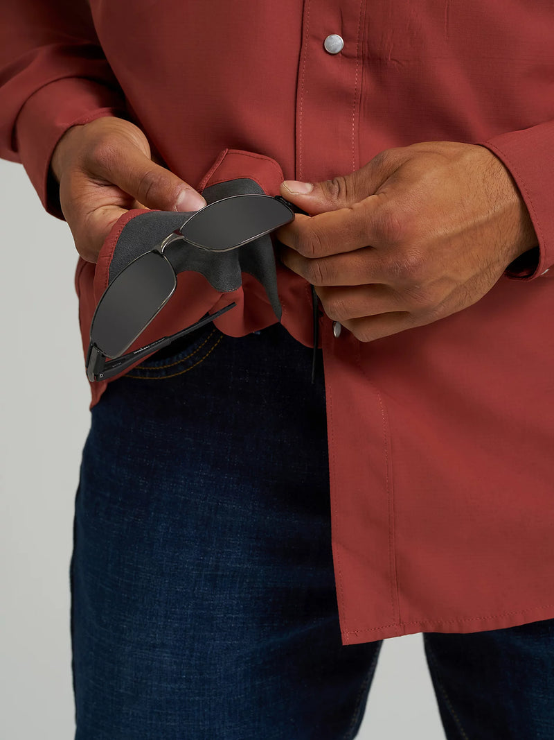 Person wearing a red shirt and blue jeans, holding a black belt.