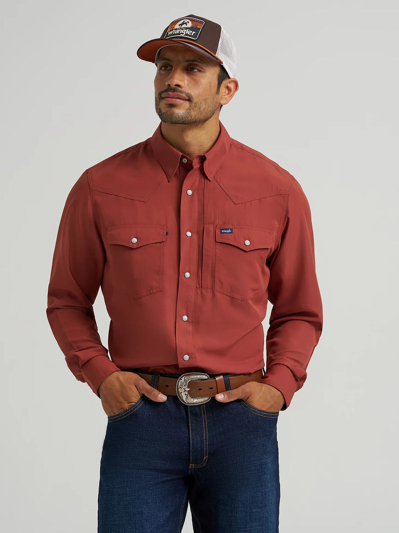 Man wearing a red shirt, blue jeans, and a cap with a visible brand logo on a plain background