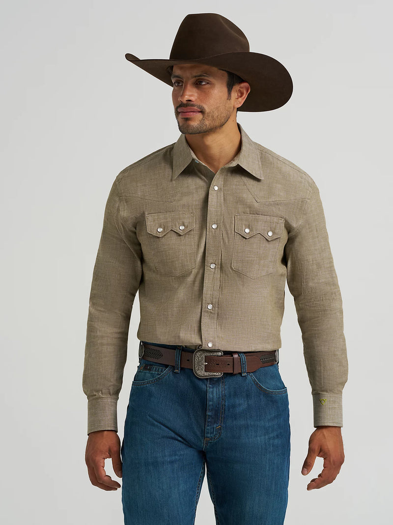 Man wearing a brown cowboy hat, beige long-sleeve shirt, and blue jeans on a gray background