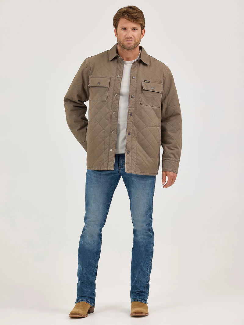 Man wearing a brown quilted jacket, white shirt, and blue jeans on a white background