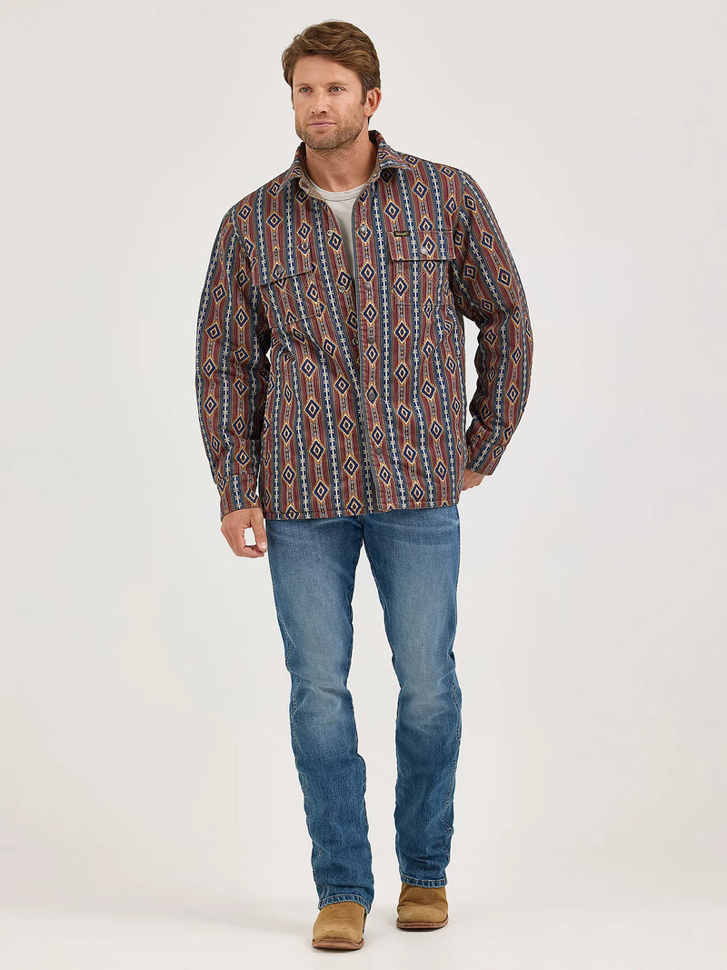 Man wearing a patterned shirt and jeans on a white background