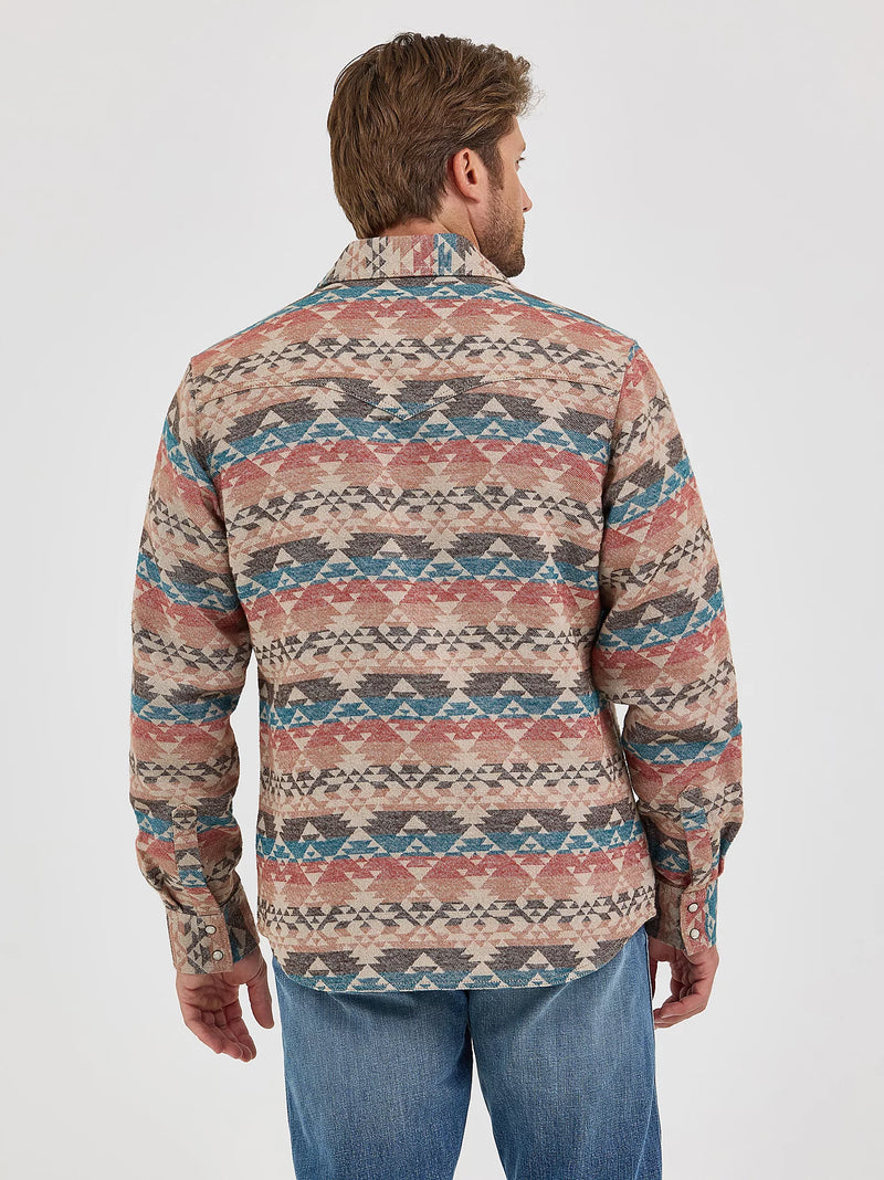 Man wearing a patterned shirt and jeans on a white background