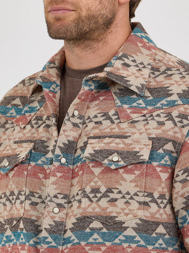 Man wearing a patterned shirt with a geometric design on a plain background