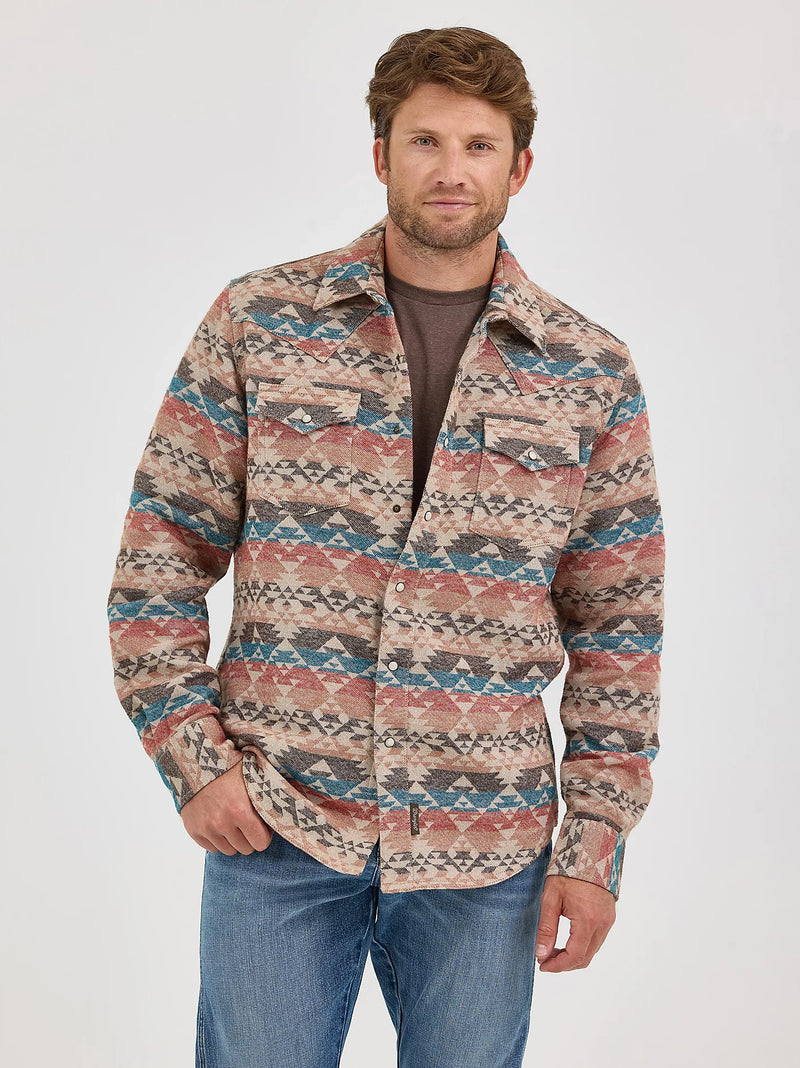 Man wearing a patterned shirt and jeans on a white background