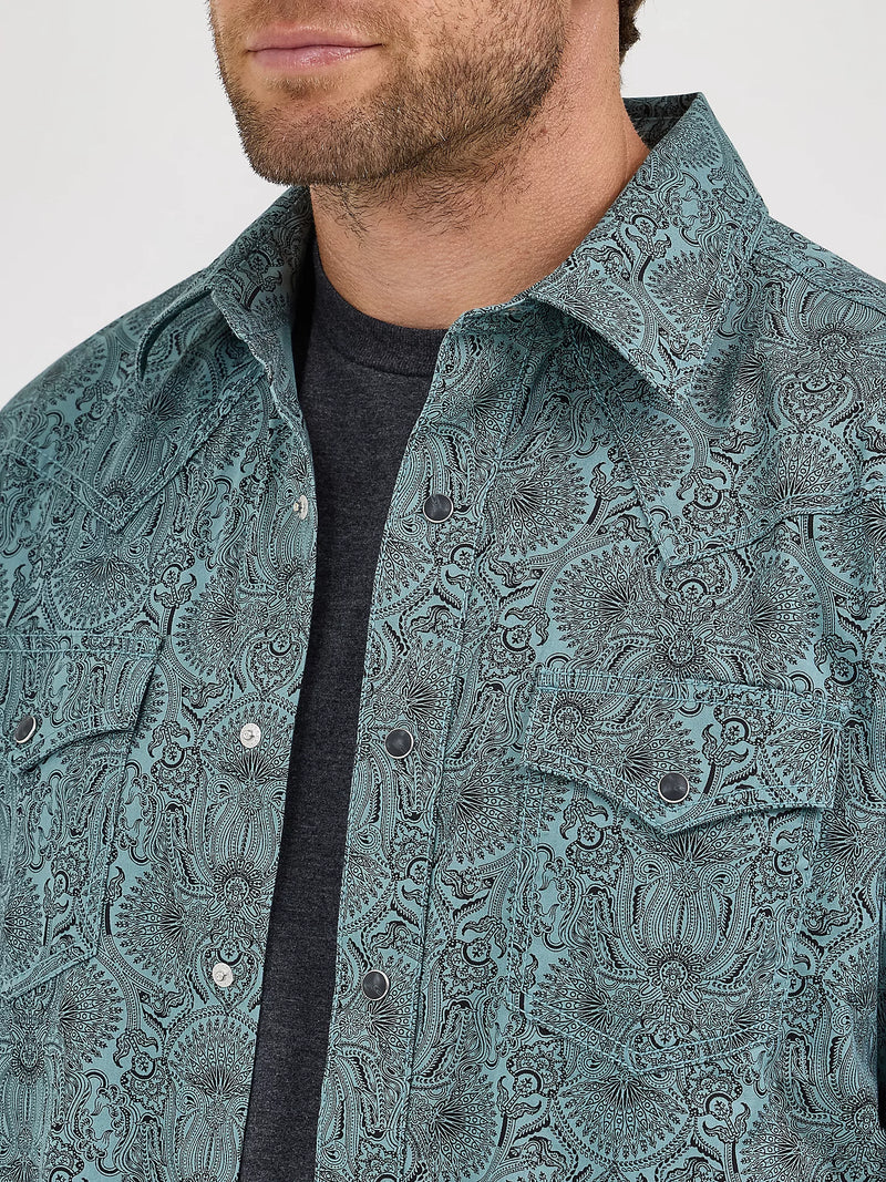 Man wearing a teal patterned shirt with a plain background