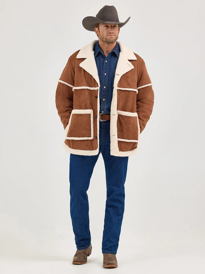 Man wearing a brown shearling coat with white trim, blue shirt, and jeans on a white background