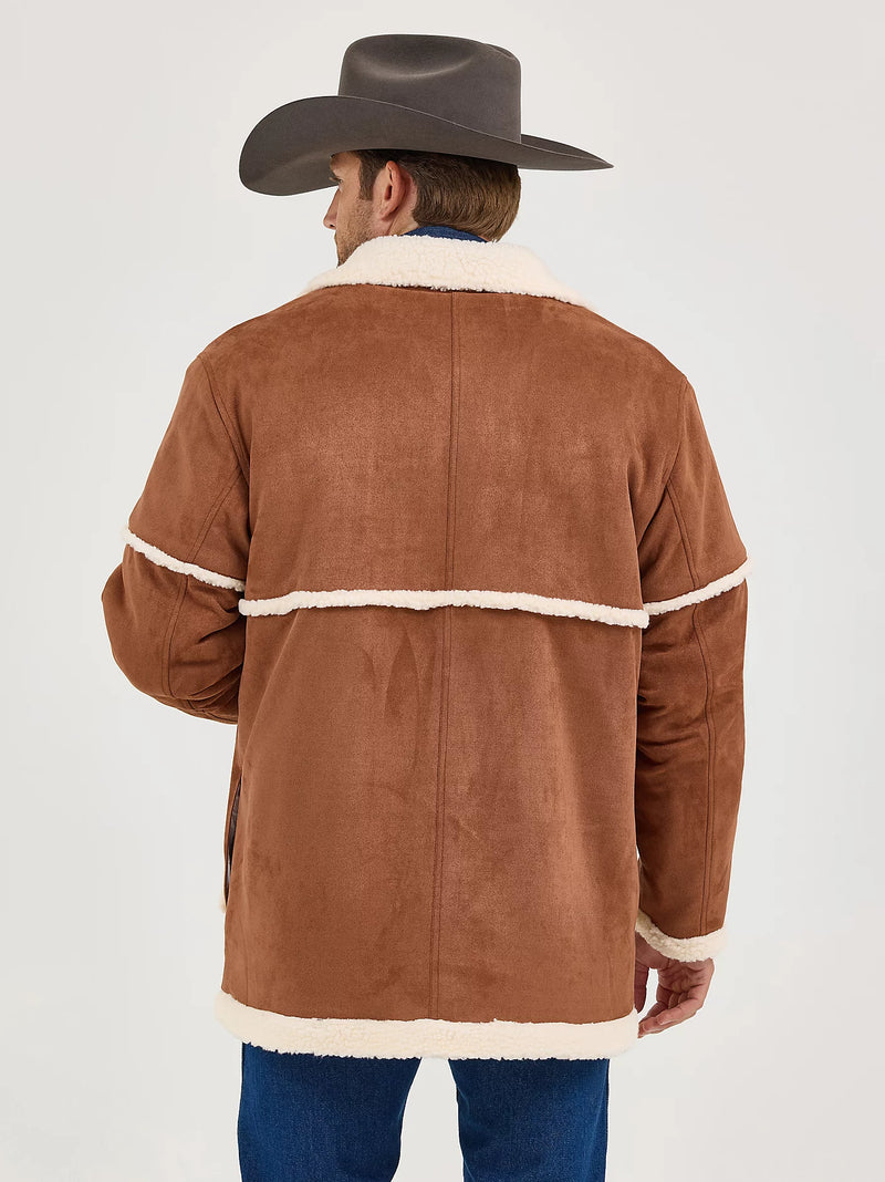 Man wearing a brown suede jacket with white trim and a cowboy hat on a light gray background
