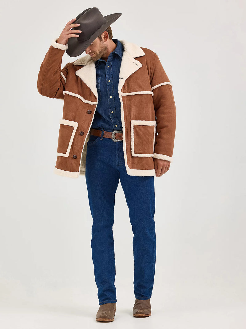 Man wearing a brown shearling jacket with white lining, blue denim shirt, and jeans on a white background