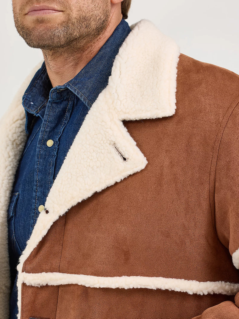 Brown shearling jacket with white fur lining worn by a person, against a neutral background.