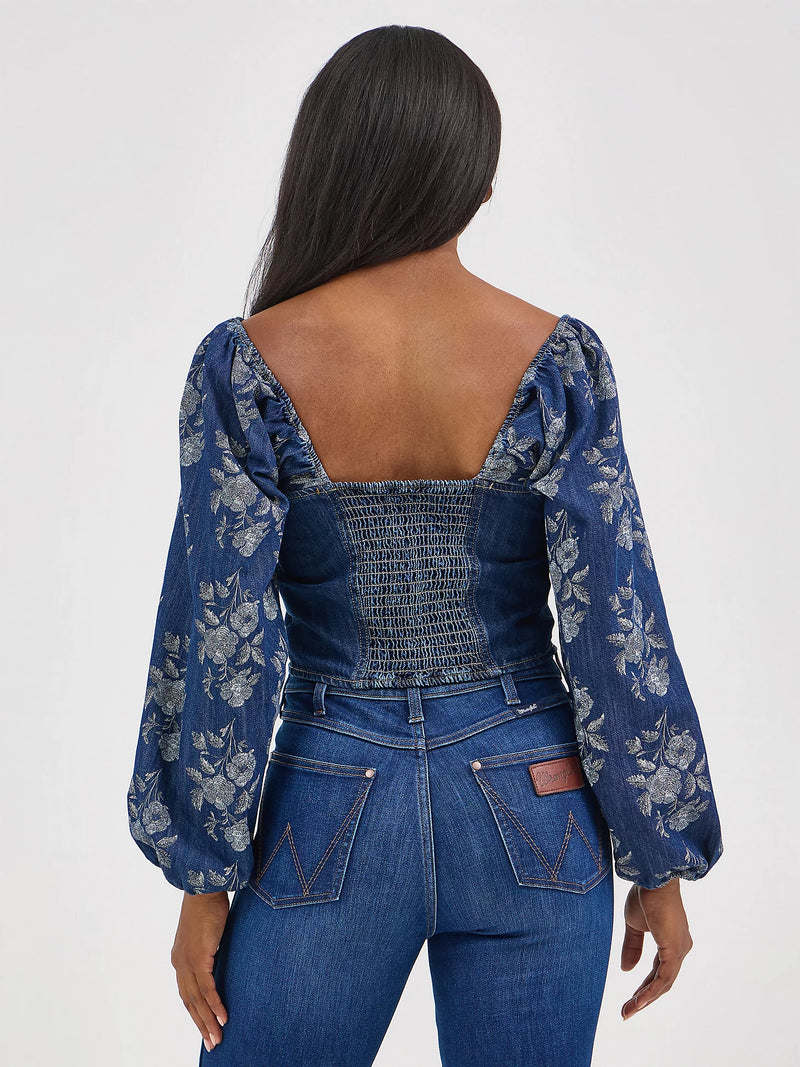 Woman wearing a blue floral blouse and jeans on a white background