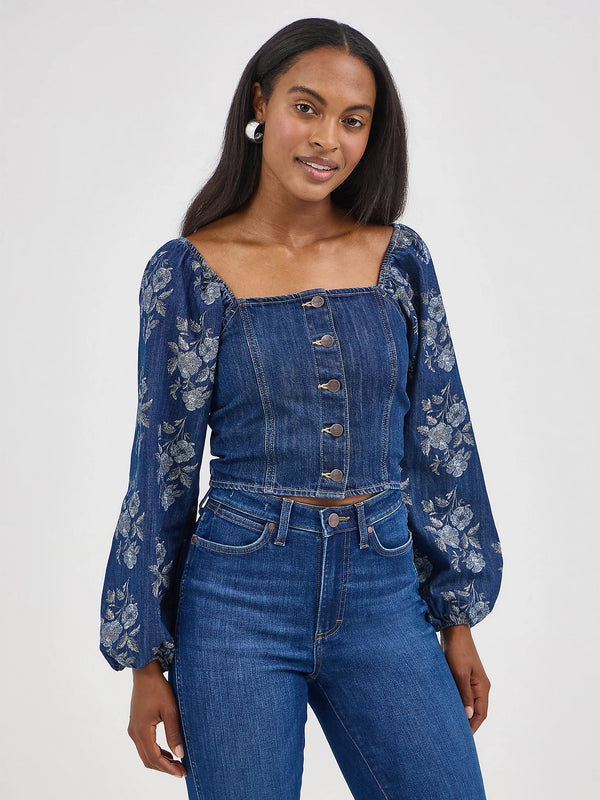 Woman wearing a denim outfit with floral embroidery on a white background