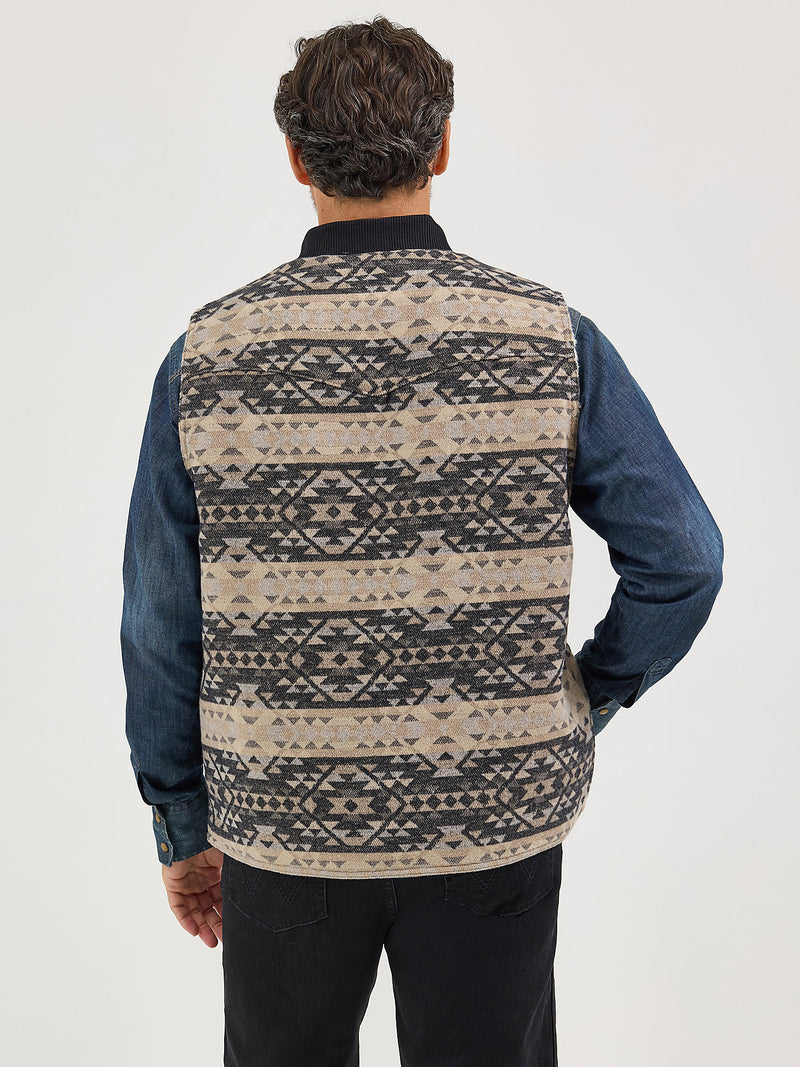 Person wearing a patterned vest over a blue shirt on a white background