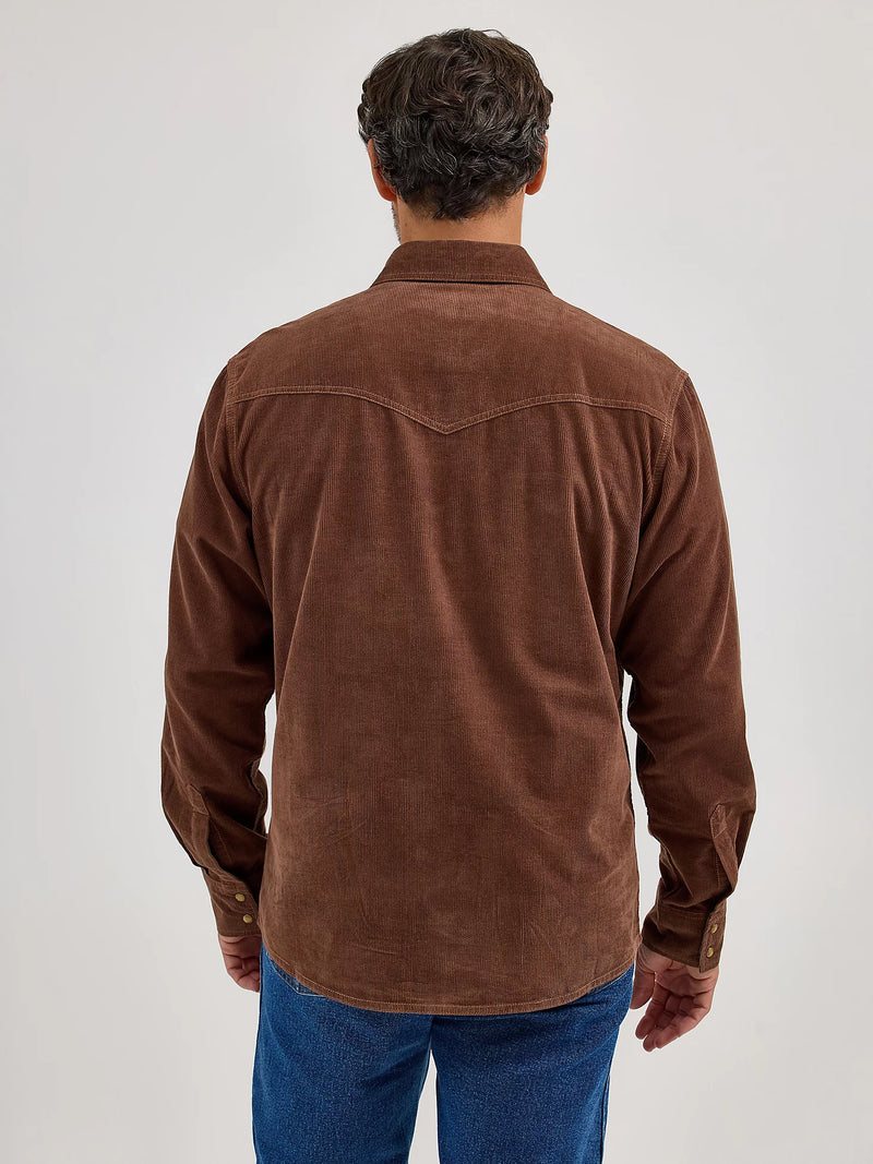 Man wearing a brown corduroy shirt and blue jeans against a white background