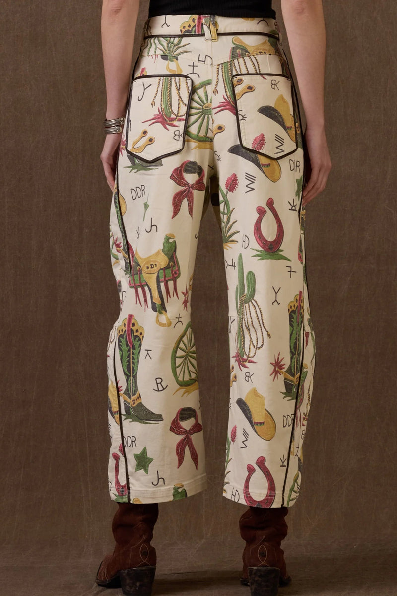 Person wearing patterned pants with cowboy-themed designs on a brown background