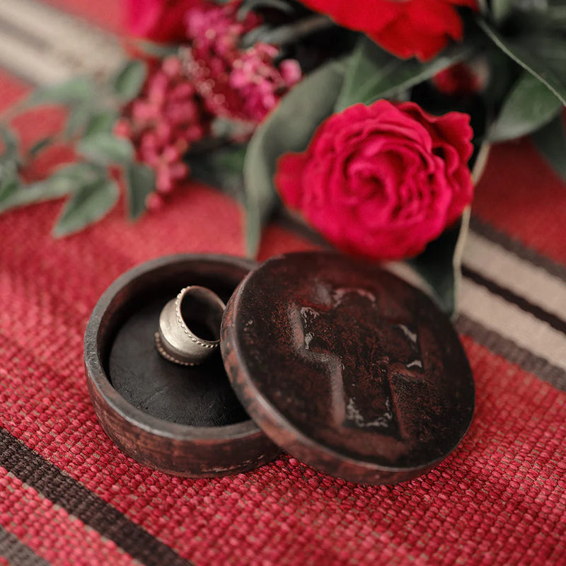 Wooden box with a ring on a red fabric background with red roses.