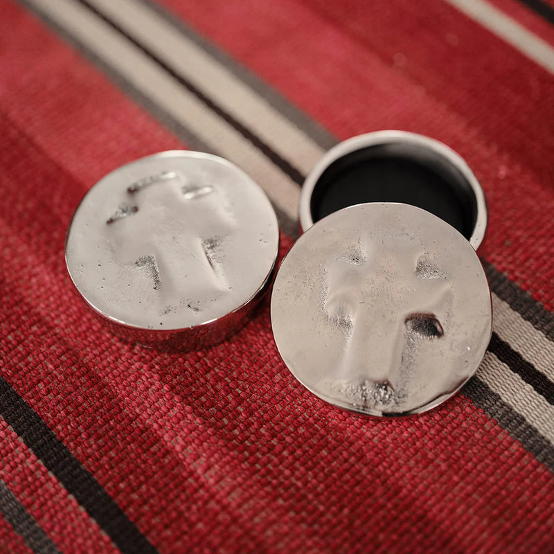 Metallic sand dollar earrings on a red textured background