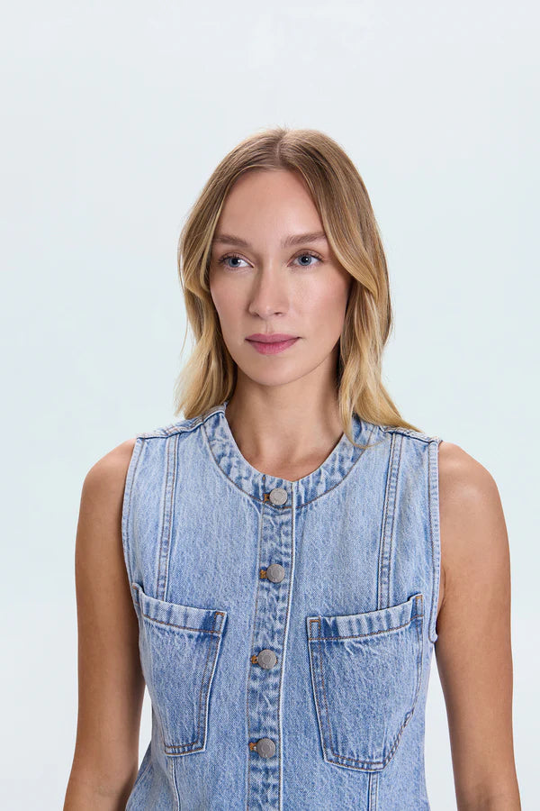 Woman wearing a denim sleeveless jacket against a light blue background