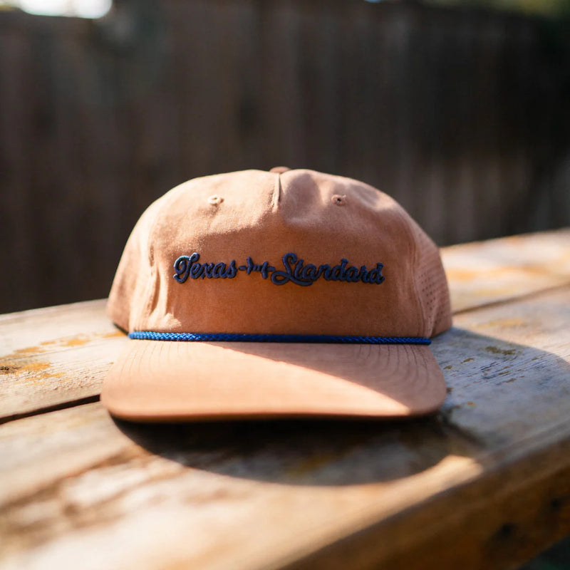 Brown cap with 'Texas Standard' embroidery on a wooden surface