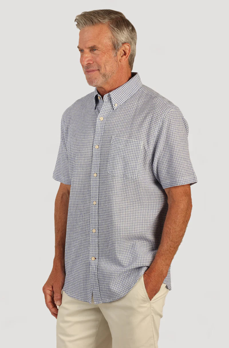 Man wearing short sleeve shirt with button front, collar, blue and white checker print and single breast pocket