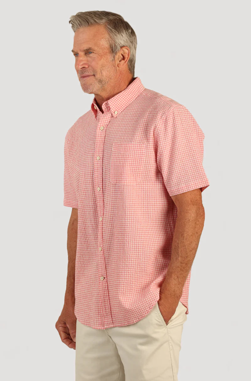 Man wearing short sleeve button front shirt with collar, pink and white checker print and single breast pocket